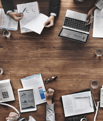 Aerial view of people sitting at a table with laptops and paperwork in front of them